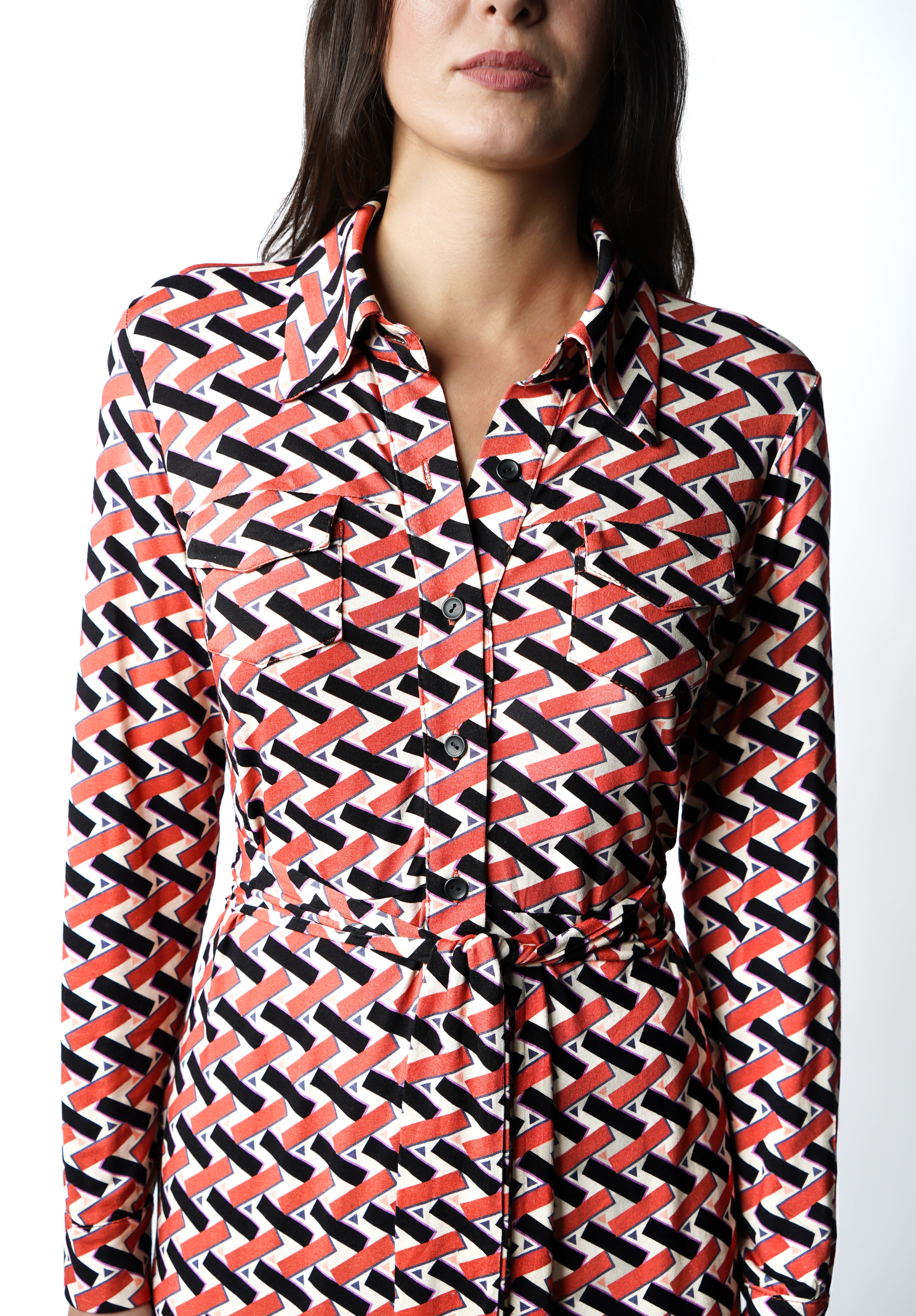 Robe à imprimé géométrique rouge noir et blanc. Coupe mi-longue à l’élégance naturelle. Col chemisier, boutonnage intégral et poche poitrine boutonnée. Bas légèrement évasé et ceinture amovible à nouer pour structurer la silhouette. Fabriquée en France.