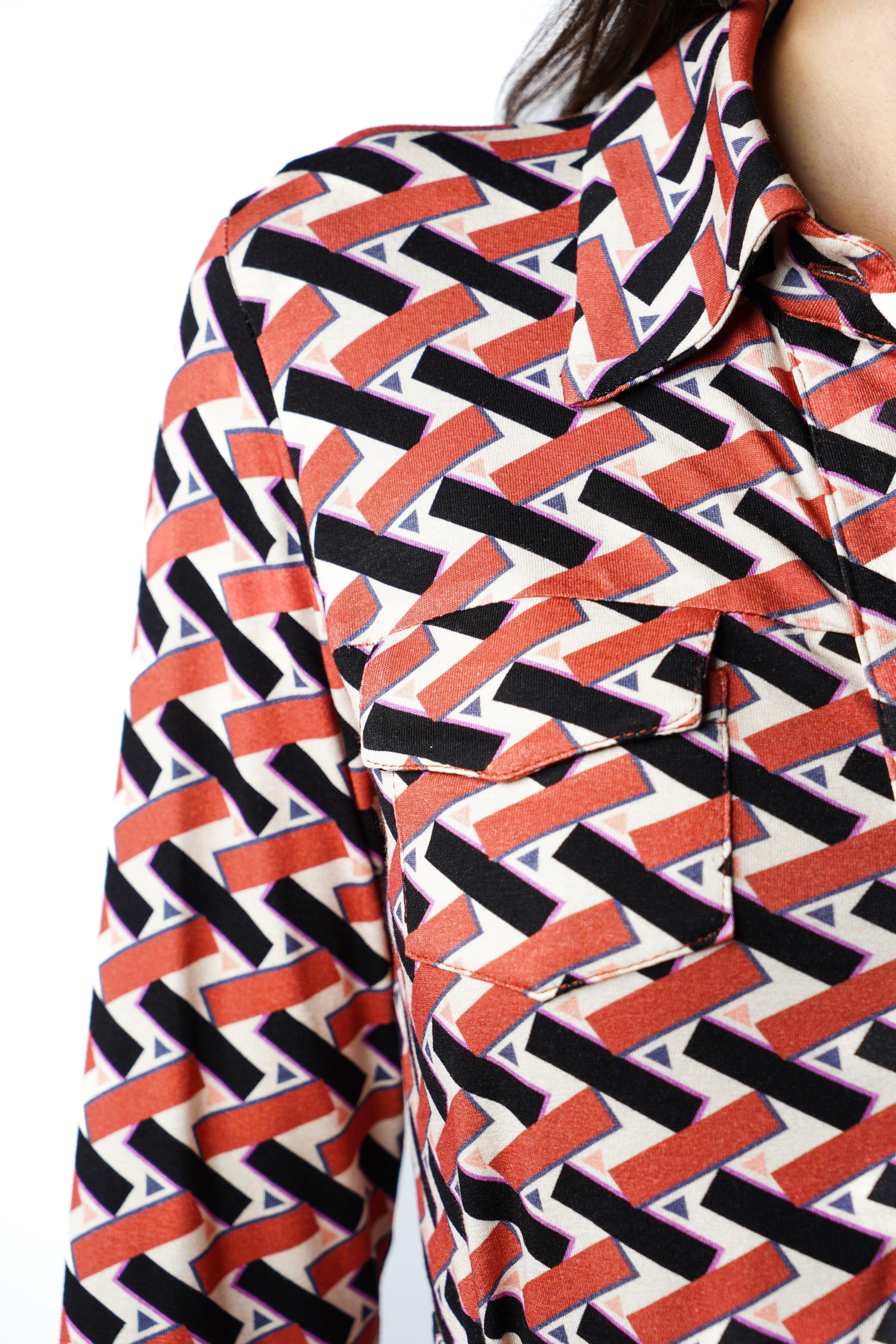 Robe à imprimé géométrique rouge noir et blanc. Coupe mi-longue à l’élégance naturelle. Col chemisier, boutonnage intégral et poche poitrine boutonnée. Bas légèrement évasé et ceinture amovible à nouer pour structurer la silhouette. Fabriquée en France.