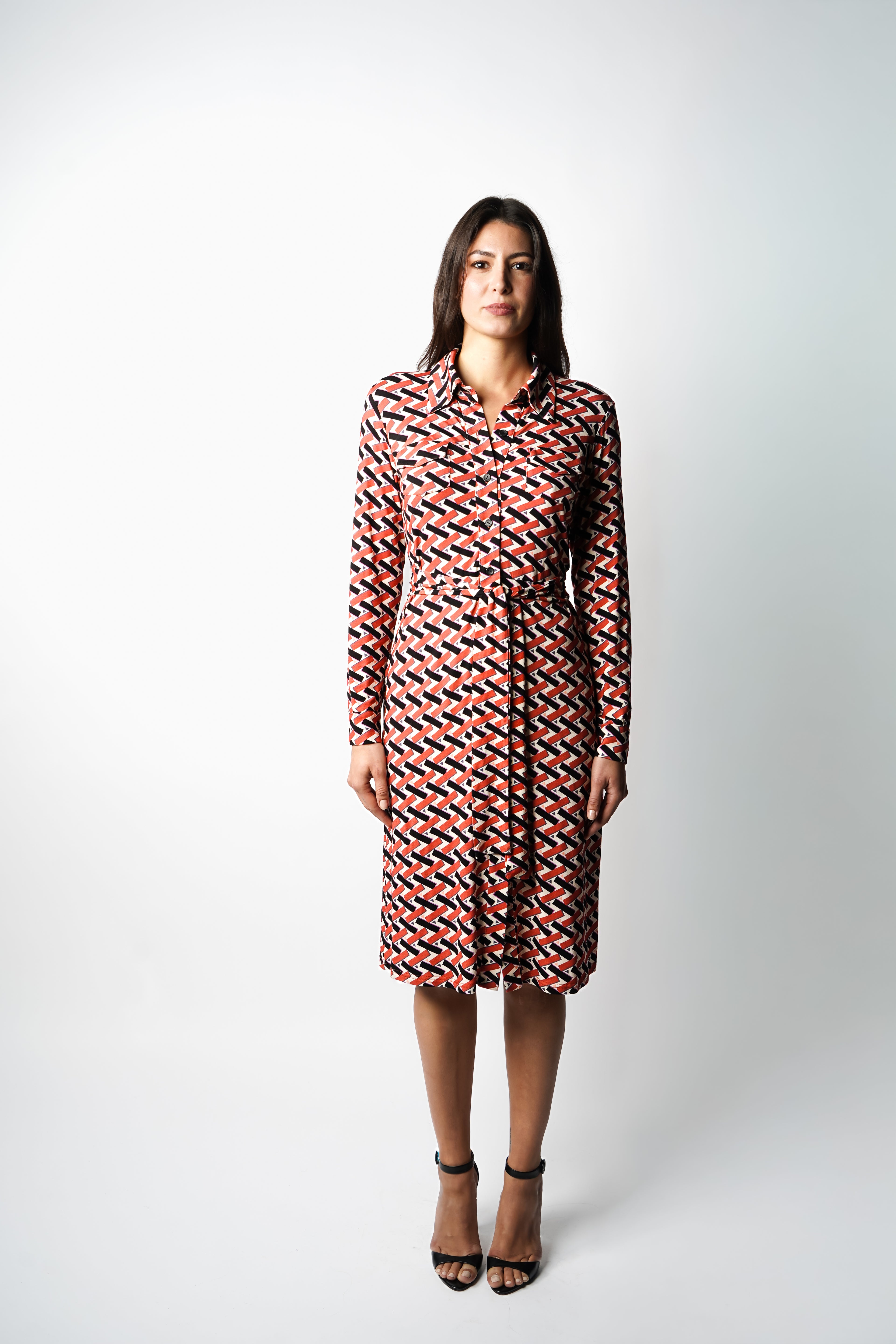 Robe à imprimé géométrique rouge noir et blanc. Coupe mi-longue à l’élégance naturelle. Col chemisier, boutonnage intégral et poche poitrine boutonnée. Bas légèrement évasé et ceinture amovible à nouer pour structurer la silhouette. Fabriquée en France.