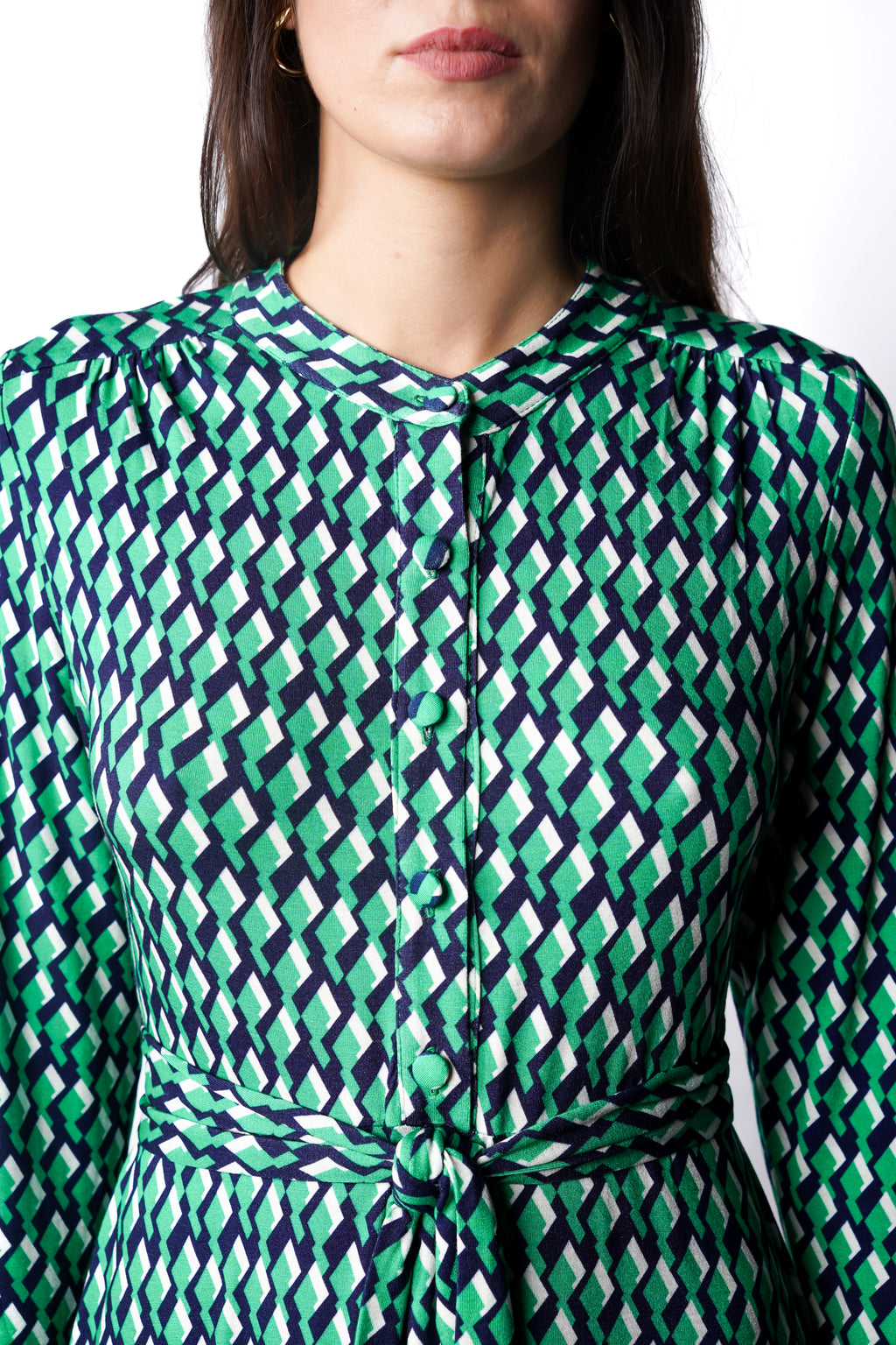 Robe à motif géométrique vert mi-longue à l’élégance naturelle. Col chemisier, boutonnage intégral et poche poitrine boutonnée. Bas légèrement évasé et ceinture amovible à nouer pour structurer la silhouette. Fabriquée en France.