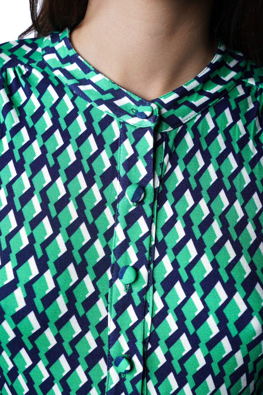 Robe à motif géométrique vert mi-longue à l’élégance naturelle. Col chemisier, boutonnage intégral et poche poitrine boutonnée. Bas légèrement évasé et ceinture amovible à nouer pour structurer la silhouette. Fabriquée en France.