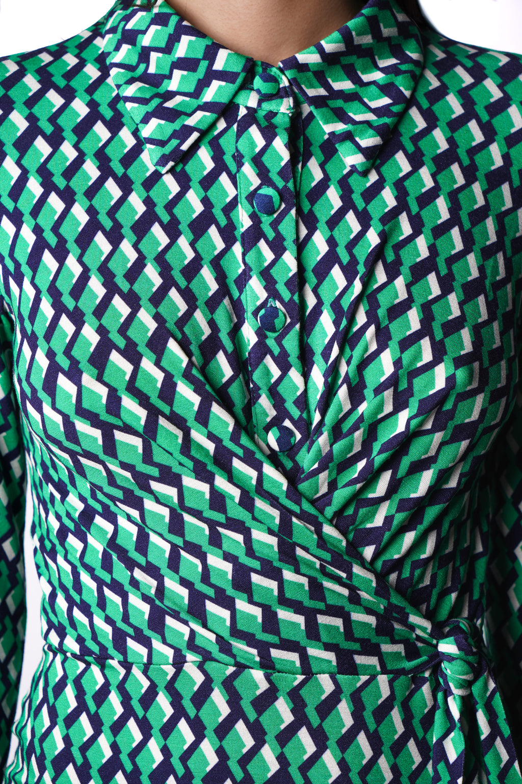 Robe à imprimé vert géométrique mi-longue, coupe fluide et moderne. Col chemisier et boutonnage caché. Drapé croisé sur le côté gauche pour une touche sophistiquée. Bas légèrement évasé. Fabriquée en France.