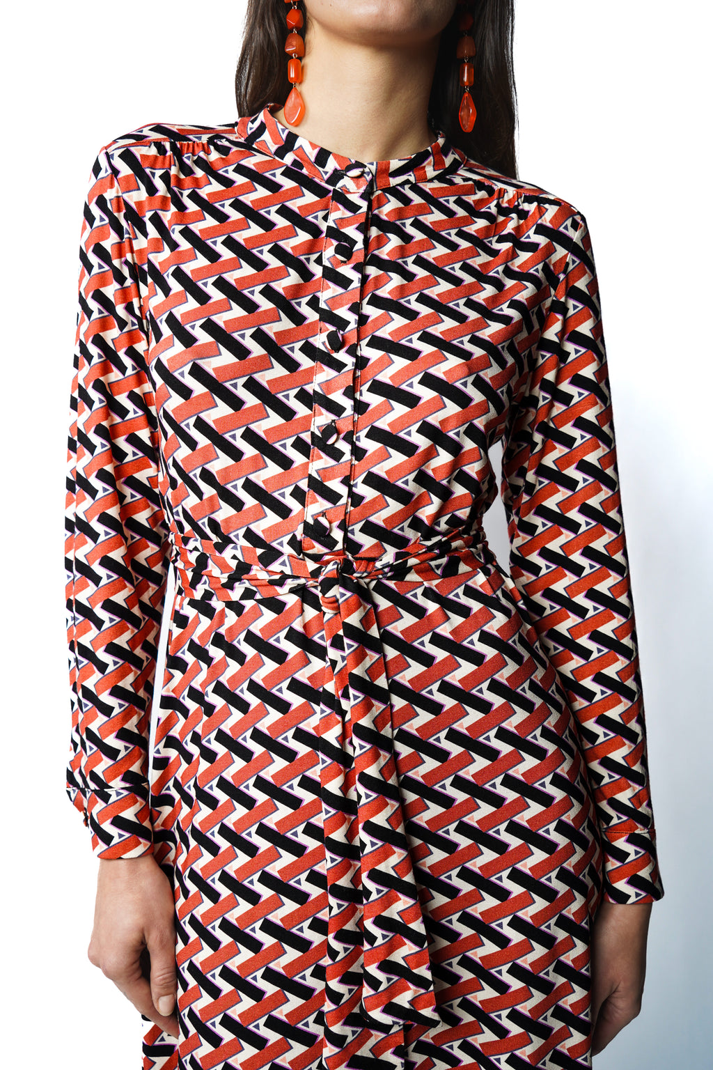 Robe mi-longue au tombé fluide. Encolure ronde, patte de boutonnage et fronces délicates sous les épaules. Manches boutonnées et ceinture à nouer pour une allure féminine et raffinée. Fabriquée en France.