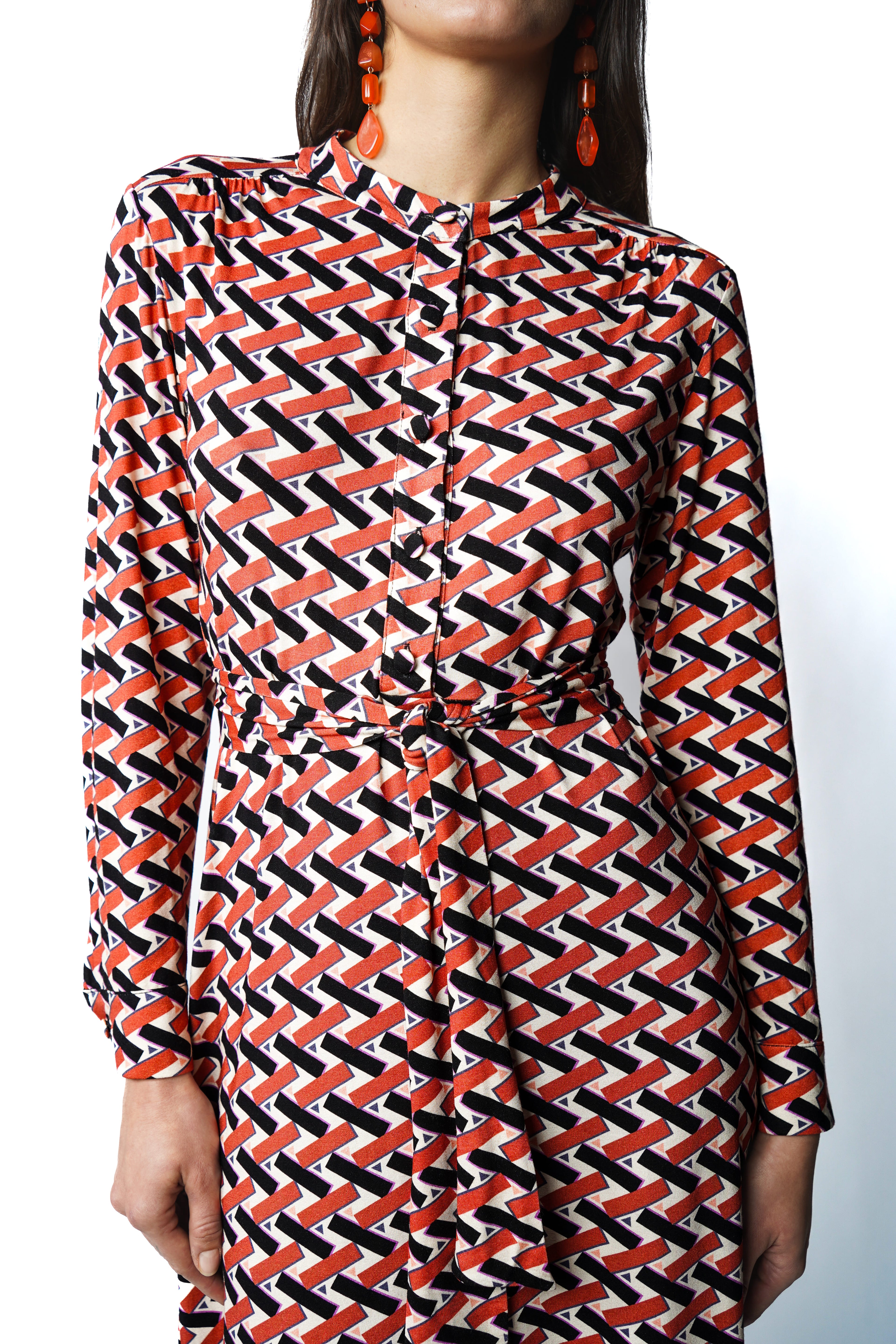 Robe mi-longue au tombé fluide. Encolure ronde, patte de boutonnage et fronces délicates sous les épaules. Manches boutonnées et ceinture à nouer pour une allure féminine et raffinée. Fabriquée en France.