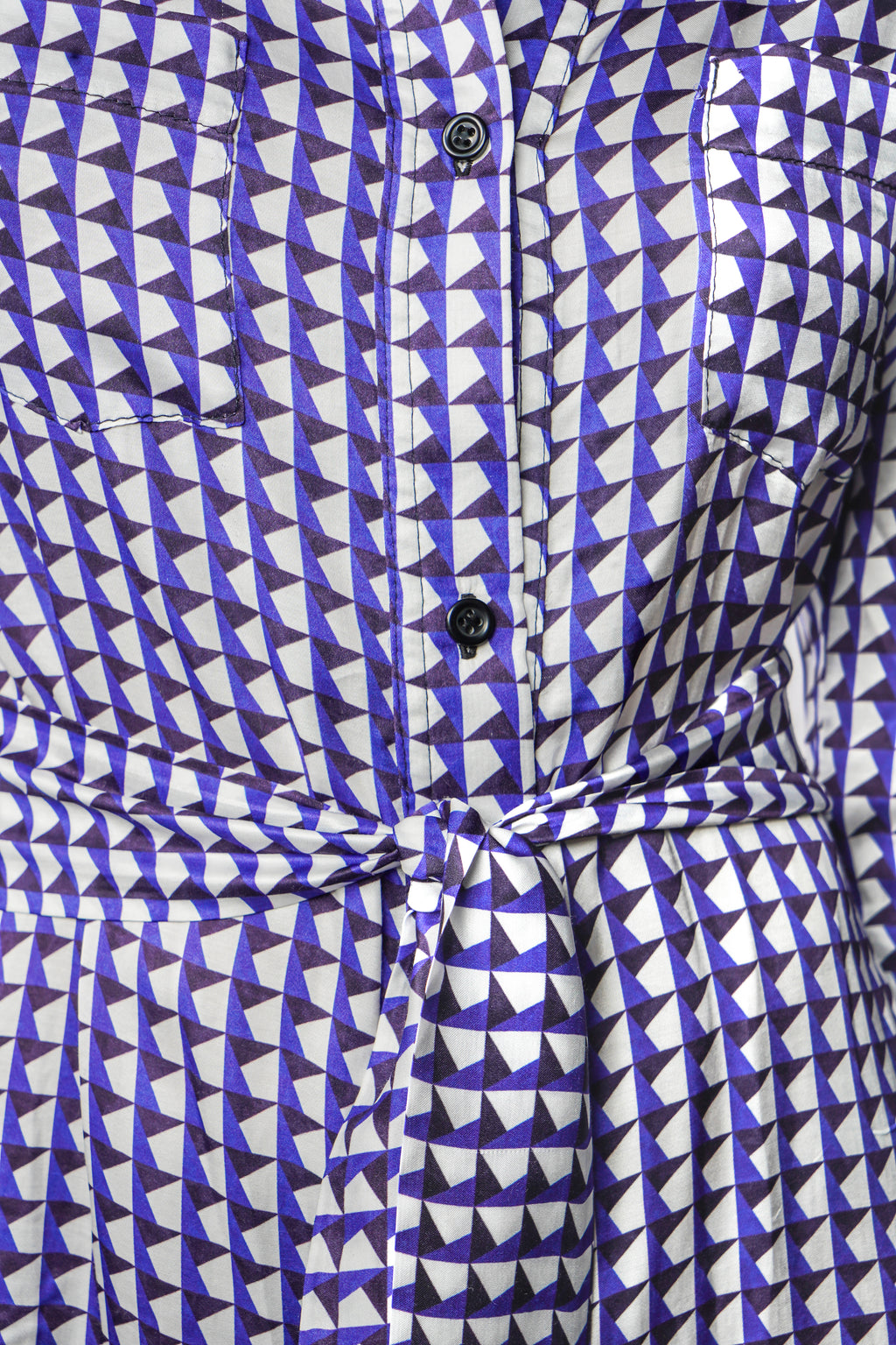 Robe à motif bleu mi-longue à l’élégance décontractée. Col chemisier, boutonnage intégral et poche poitrine. Manches boutonnées et ceinture assortie à nouer pour une allure féminine et moderne. Fabriquée en france.