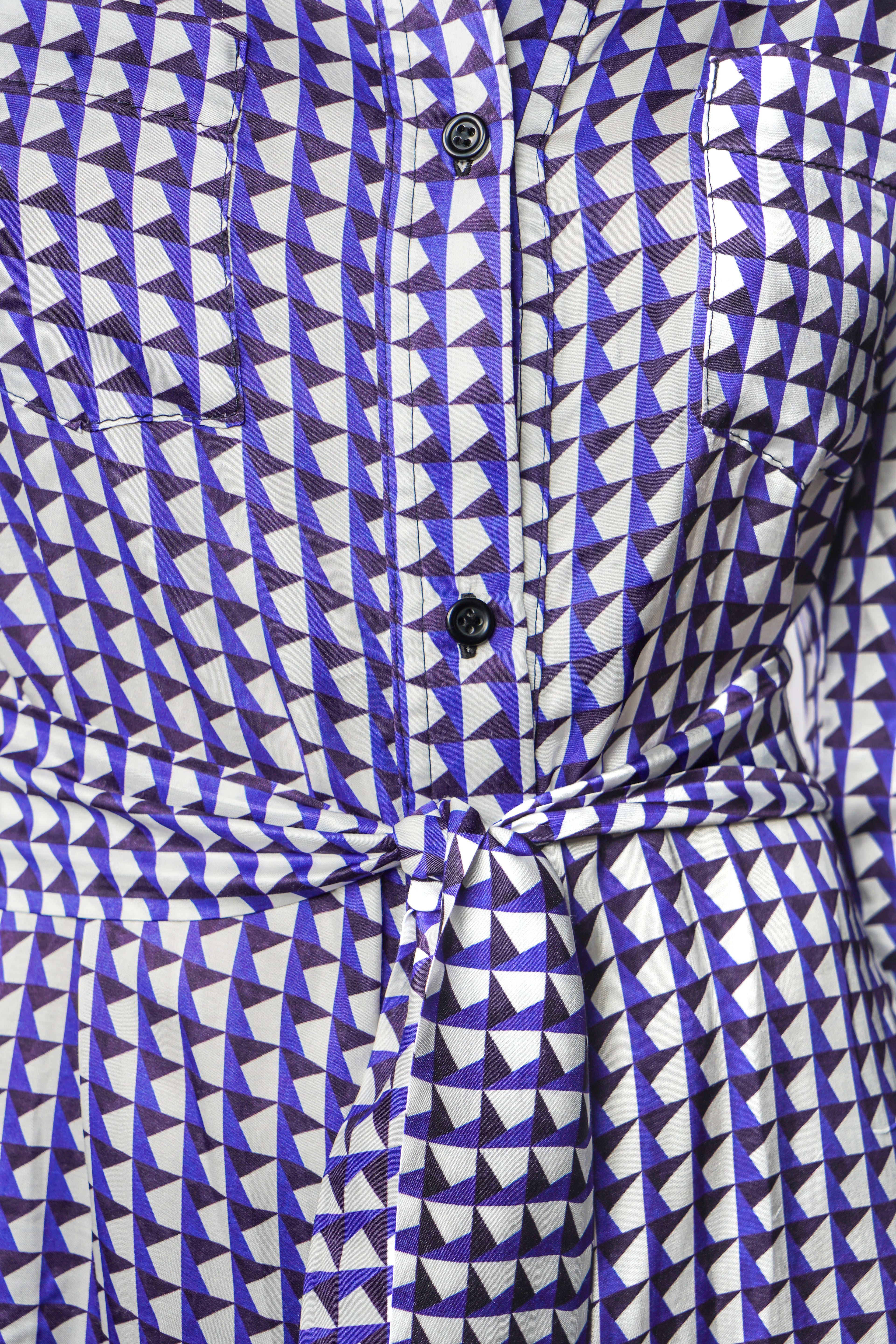 Robe à motif bleu mi-longue à l’élégance décontractée. Col chemisier, boutonnage intégral et poche poitrine. Manches boutonnées et ceinture assortie à nouer pour une allure féminine et moderne. Fabriquée en france.