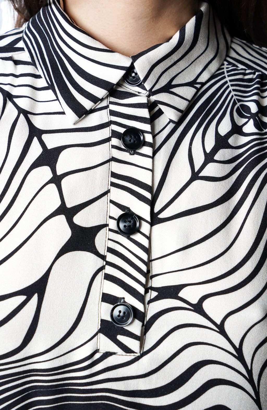 Robe polo à motif rayé zèbre, hauteur genoux. Col chemisier et patte de boutonnage pour un esprit chic et contemporain. Manches longues et poches discrètes dans les coutures. Fabriquée en France.