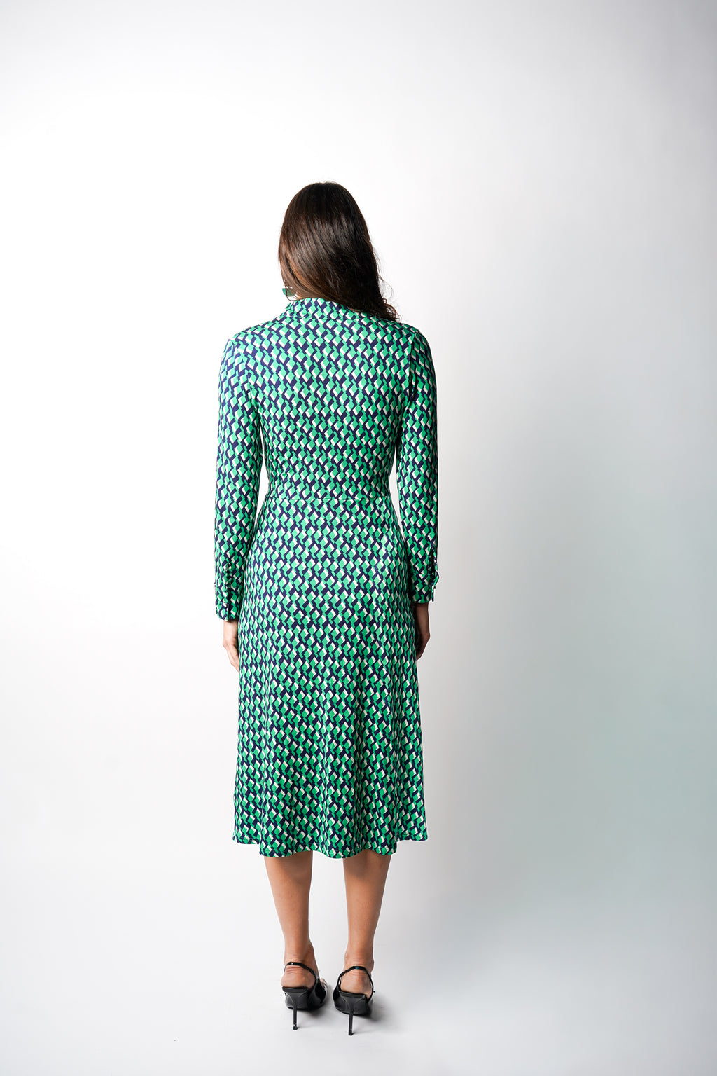 Robe à imprimé vert géométrique mi-longue, coupe fluide et moderne. Col chemisier et boutonnage caché. Drapé croisé sur le côté gauche pour une touche sophistiquée. Bas légèrement évasé. Fabriquée en France.