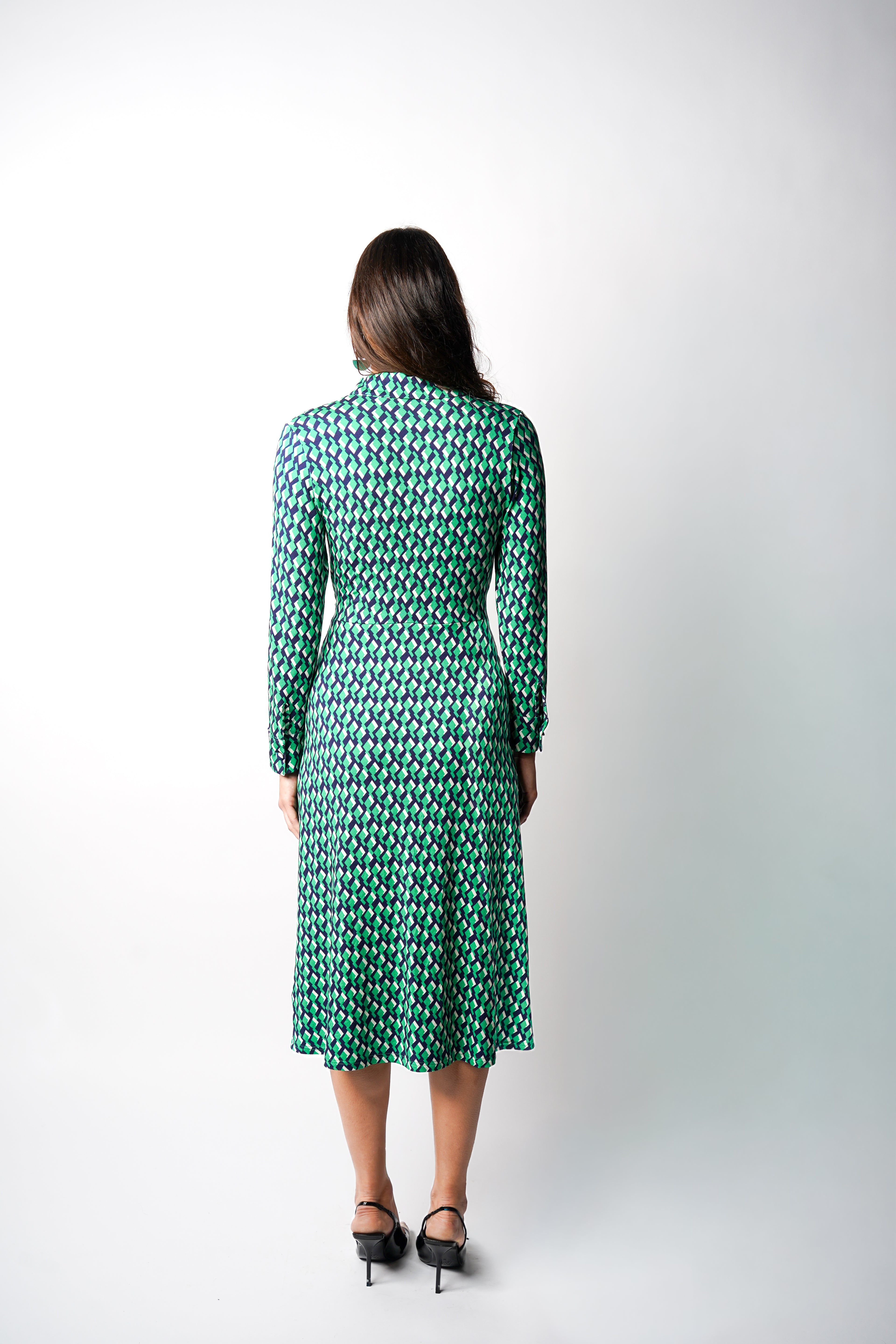 Robe à imprimé vert géométrique mi-longue, coupe fluide et moderne. Col chemisier et boutonnage caché. Drapé croisé sur le côté gauche pour une touche sophistiquée. Bas légèrement évasé. Fabriquée en France.